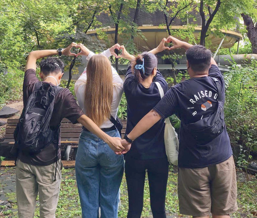 네 명의 KUBA 소속 학생들이 손으로 하트를 만들고 서 있는 뒷모습
