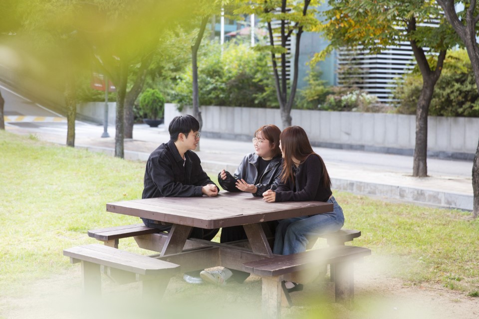 벤치에 앉아 대화를 나누는 KUPT 우수 튜터링 그룹 학생 세 명